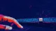 The Unclicked X A rigid fingertip stalls on a trackpad beside a crowded browser-tab strip, reflecting perfectionist
