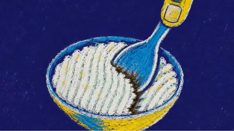 A spoon pressed into an unfinished rice bowl, symbolizing the pressure to redesign life before