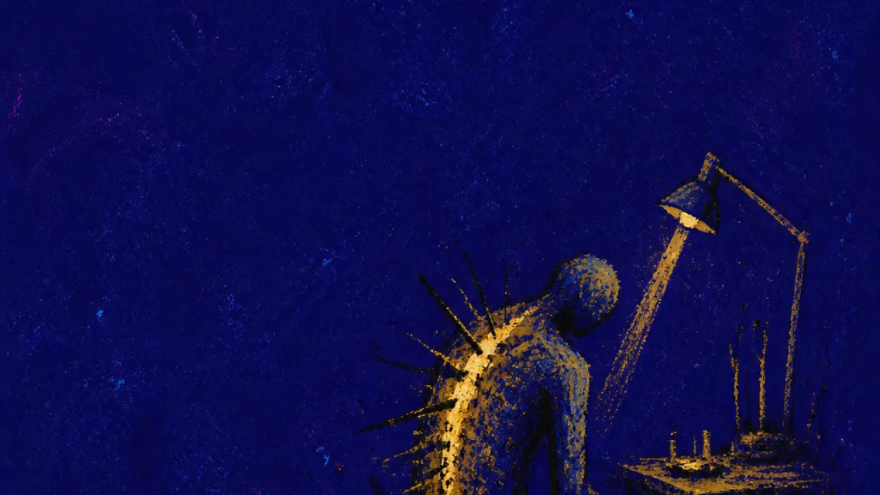 Bent Under the Workbench Light A solitary figure bent over a narrow workbench, brass light pressing into cold blue space around the spine